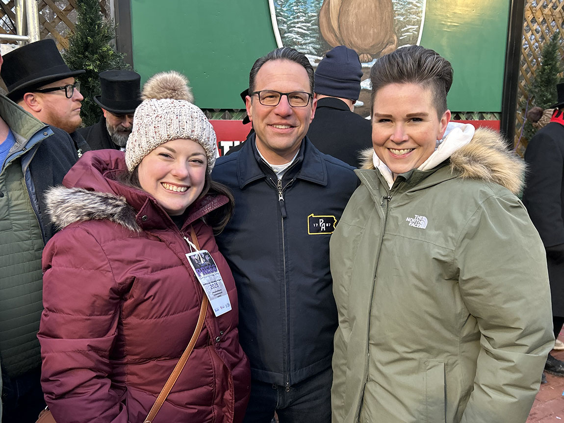 Three adults stand outside during the Groundhog Day celebration